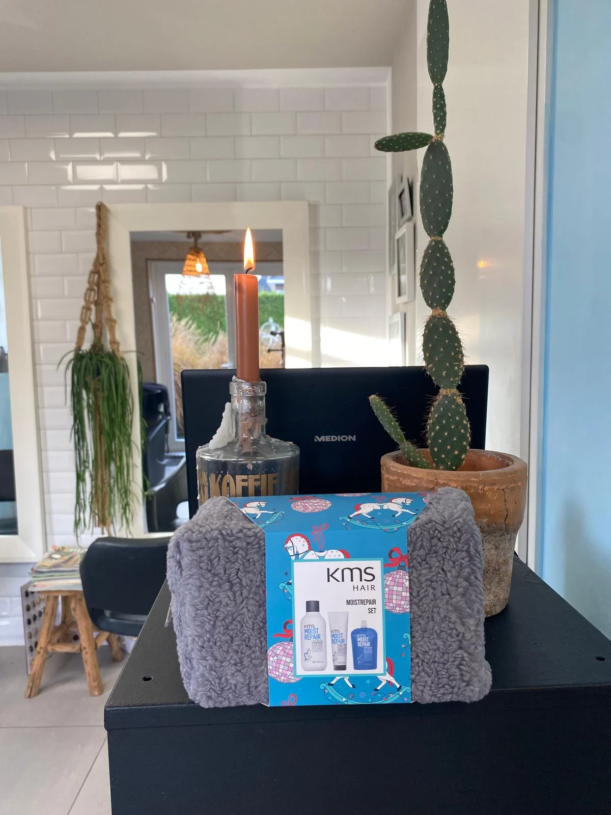 KMS Moist Repair giftset op de balie, naast een kaars en een cactus